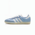 A light blue Adidas Samba sneaker with white three-stripes, white laces, and a white heel tab, set against a plain white background.