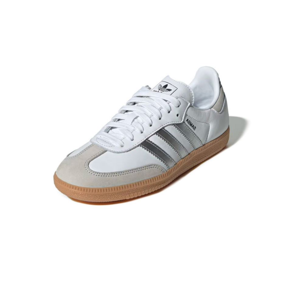 A white Adidas Samba sneaker with a light beige suede toe cap, metallic silver stripes, white laces, and a classic gum rubber sole, shown on a white background with a soft shadow.