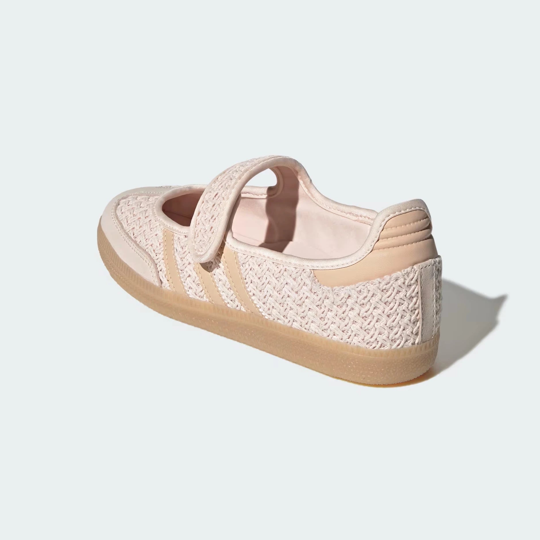 A single adidas samba janes low-top sneaker shown from a three-quarters rear angle on a light gray background. The shoe features a textured knit upper in a pale blush pink, beige leather side stripes, a matching beige heel tab, and a thick beige gum sole.