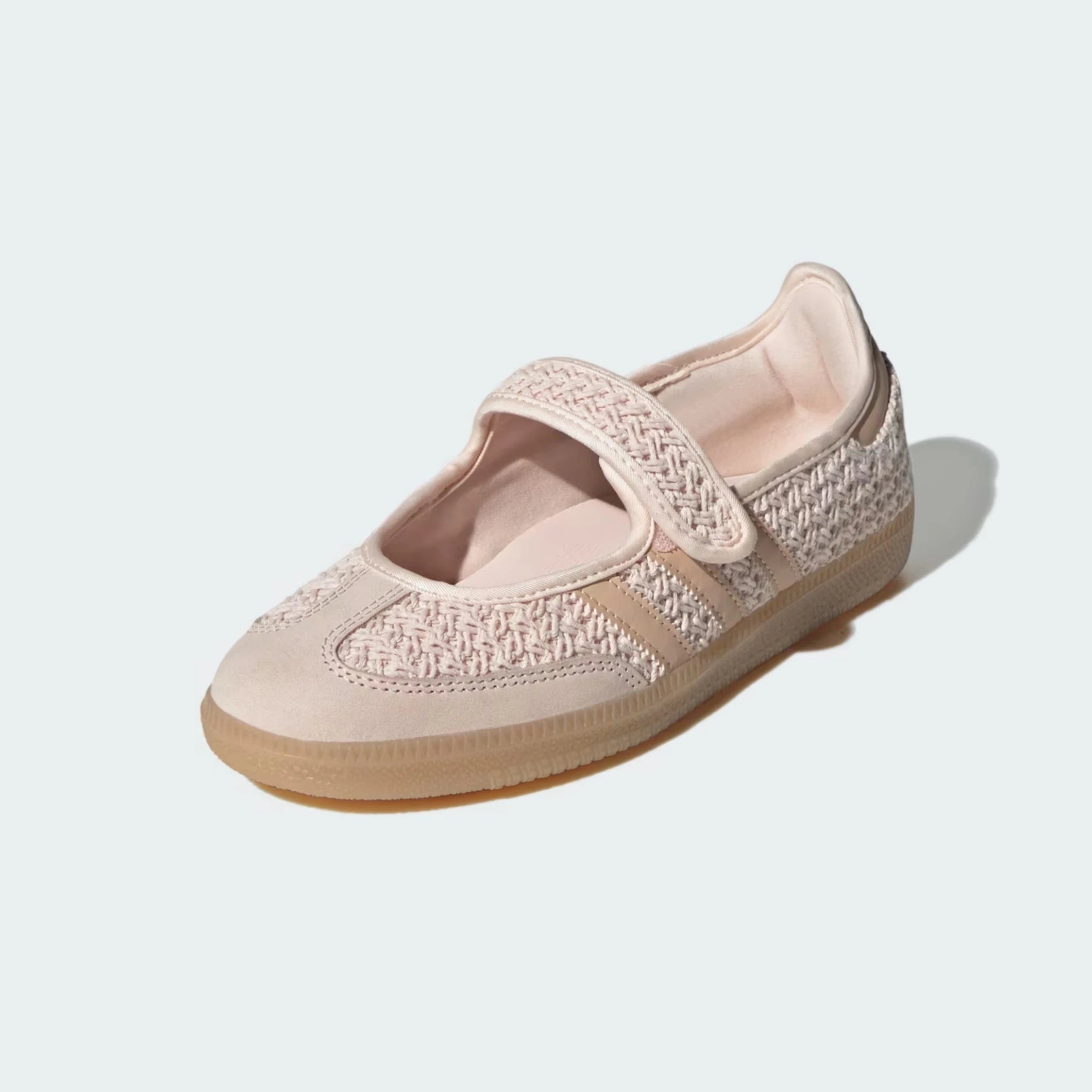 A single women's Mary Jane flat shoe in a light blush pink color, featuring a woven pattern on the toe and side straps, a hook-and-loop strap closure, and a gum sole, shown on a light gray background.