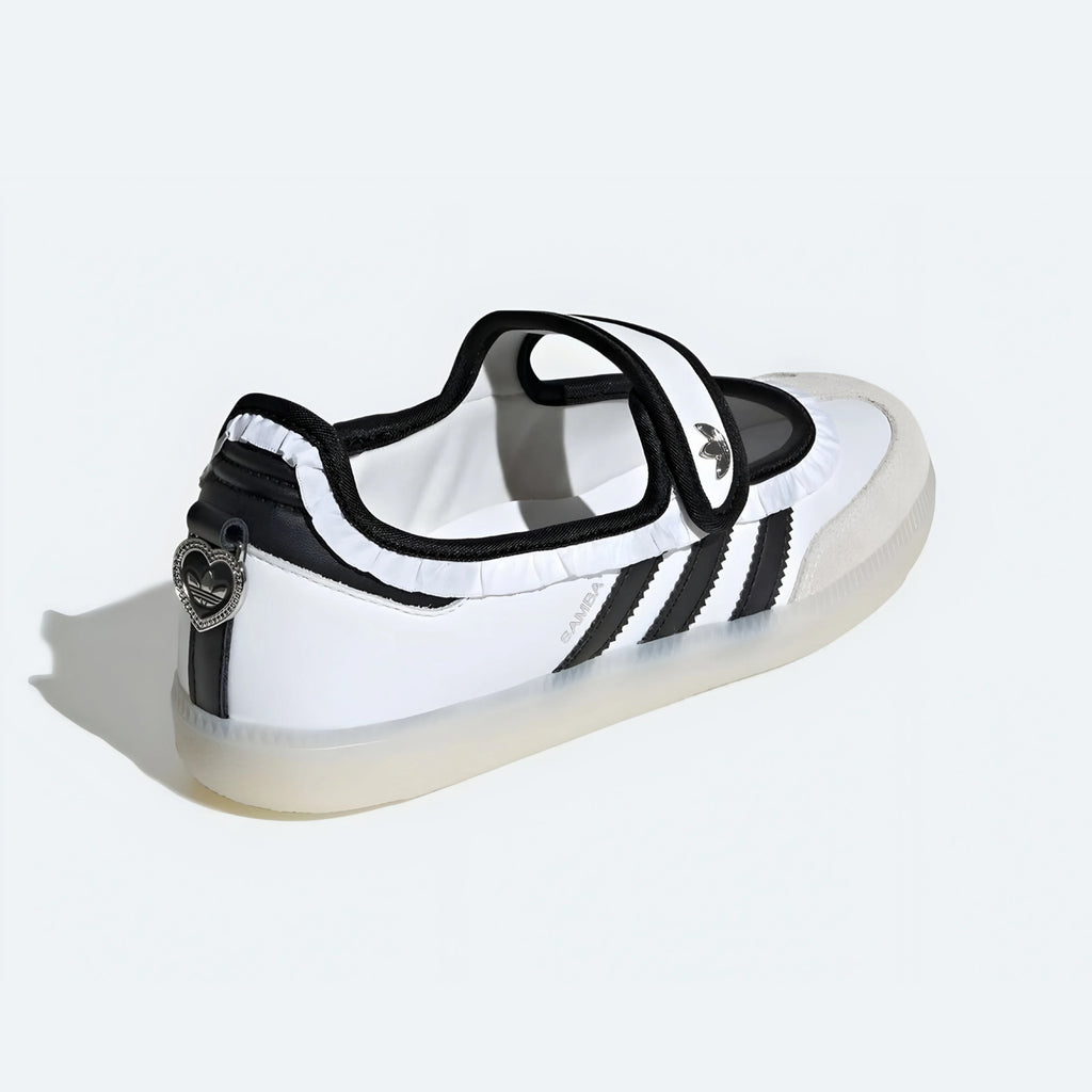 A white and black Adidas sneaker with a transparent sole, featuring three black stripes on the side and a heart-shaped metal emblem on the heel.