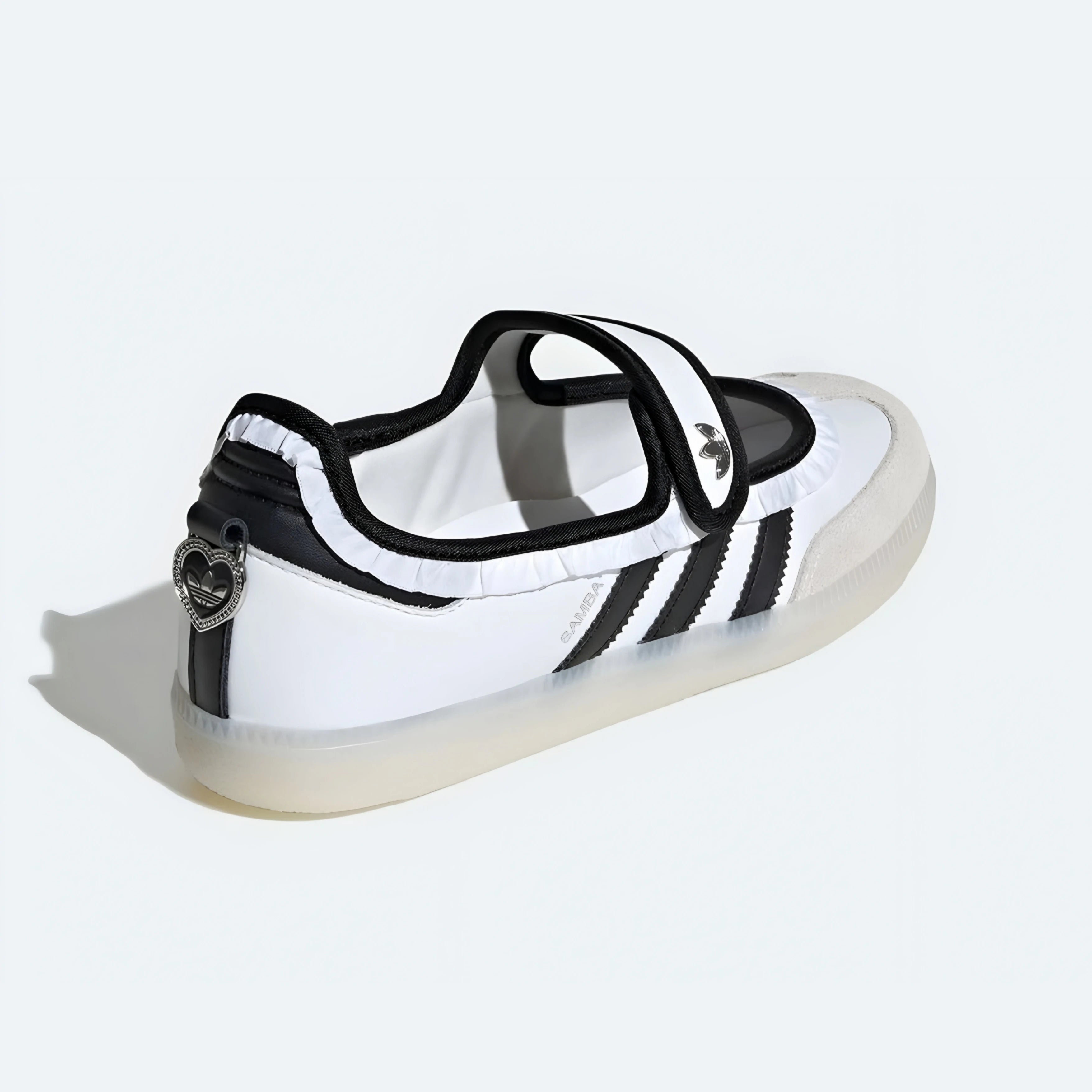 A white and black Adidas sneaker with a transparent sole, featuring three black stripes on the side and a heart-shaped metal emblem on the heel.