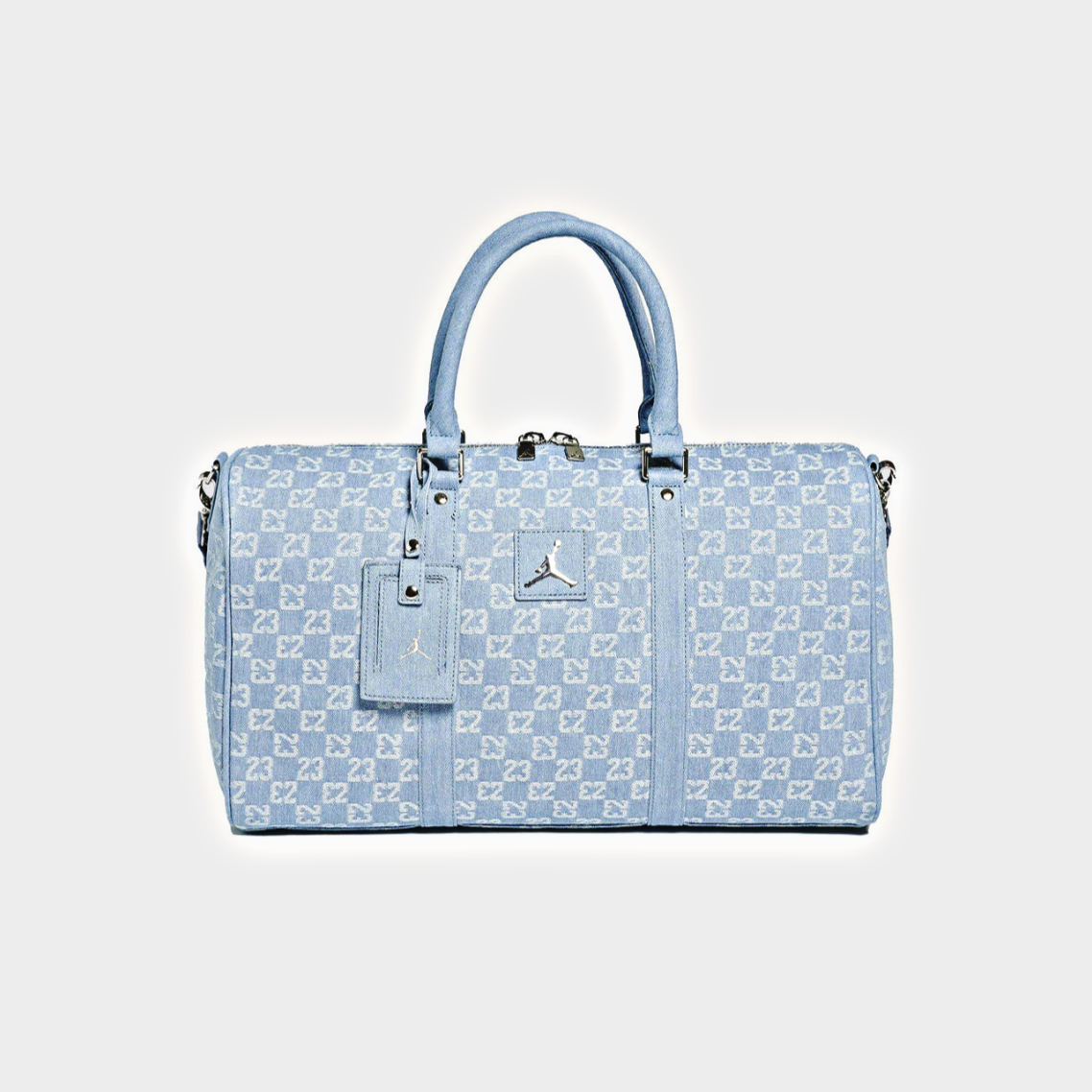 A light blue monogram duffel bag with silver hardware, featuring a top handle, a matching luggage tag, and a small silver Jordan logo on the front, set against a light gray background.
