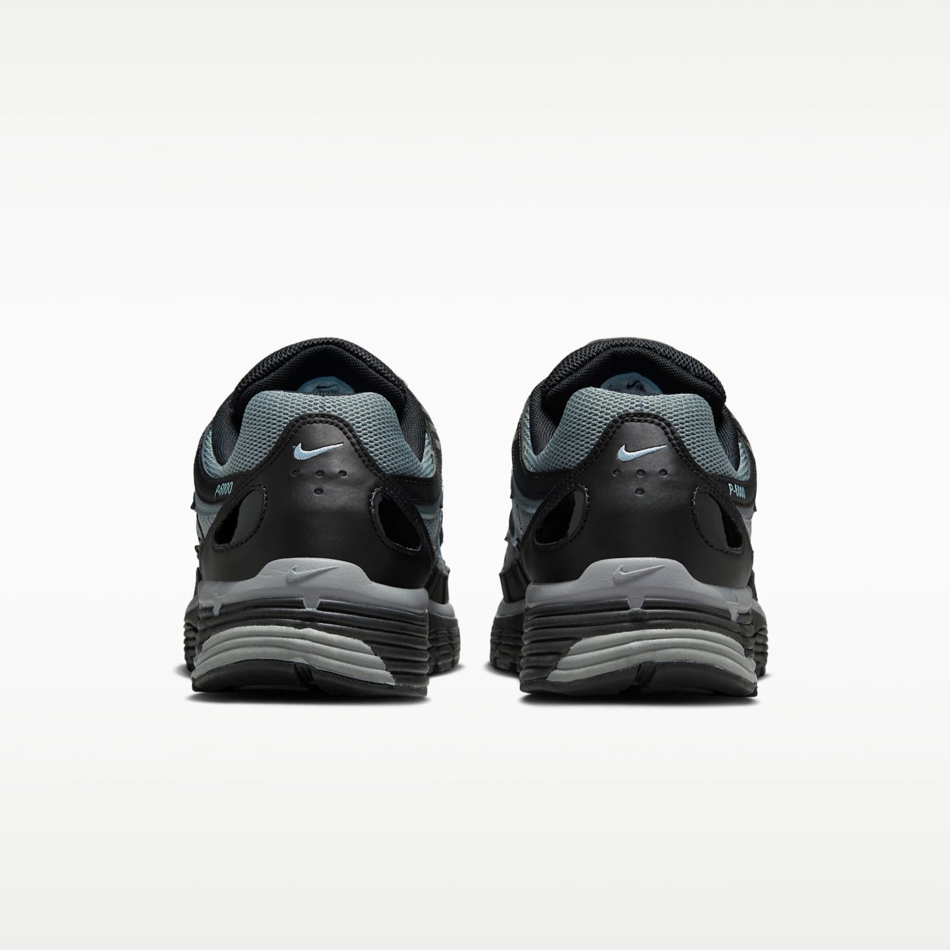 A pair of Nike P6000 running shoes shown from the rear, featuring a black and gray design with a light blue Nike Swoosh on the heel and tongue.