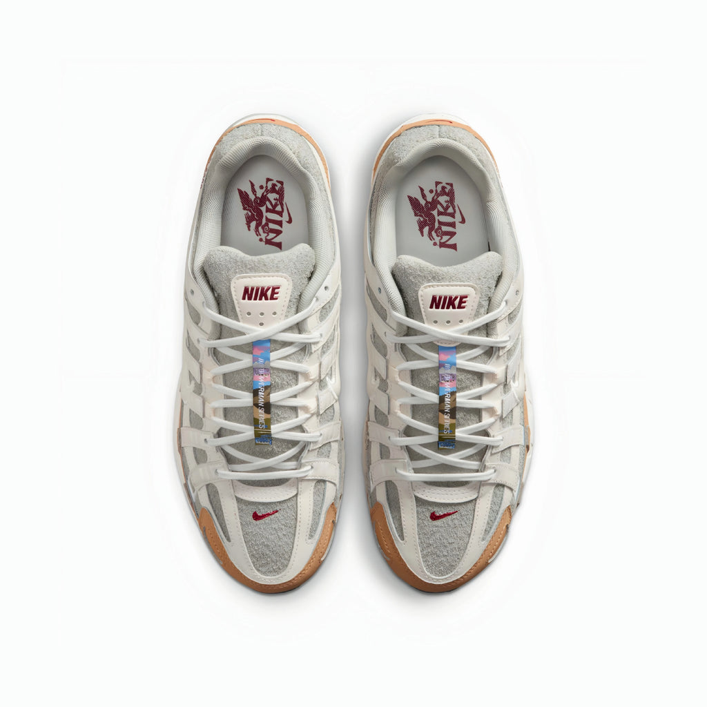 A pair of Nike P6000 sneakers shown from a top-down view on a clean white background. The shoes feature a light gray and white mesh and suede upper, white laces, a translucent gum outsole, and a red Nike Swoosh on the toe box.