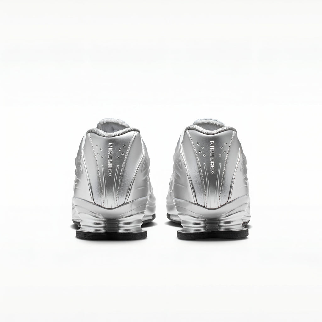 A pair of metallic silver Nike RMX sneakers shown from the back, featuring the 'FIRST STEP' branding and a clear cushioned sole, set against a plain white background.