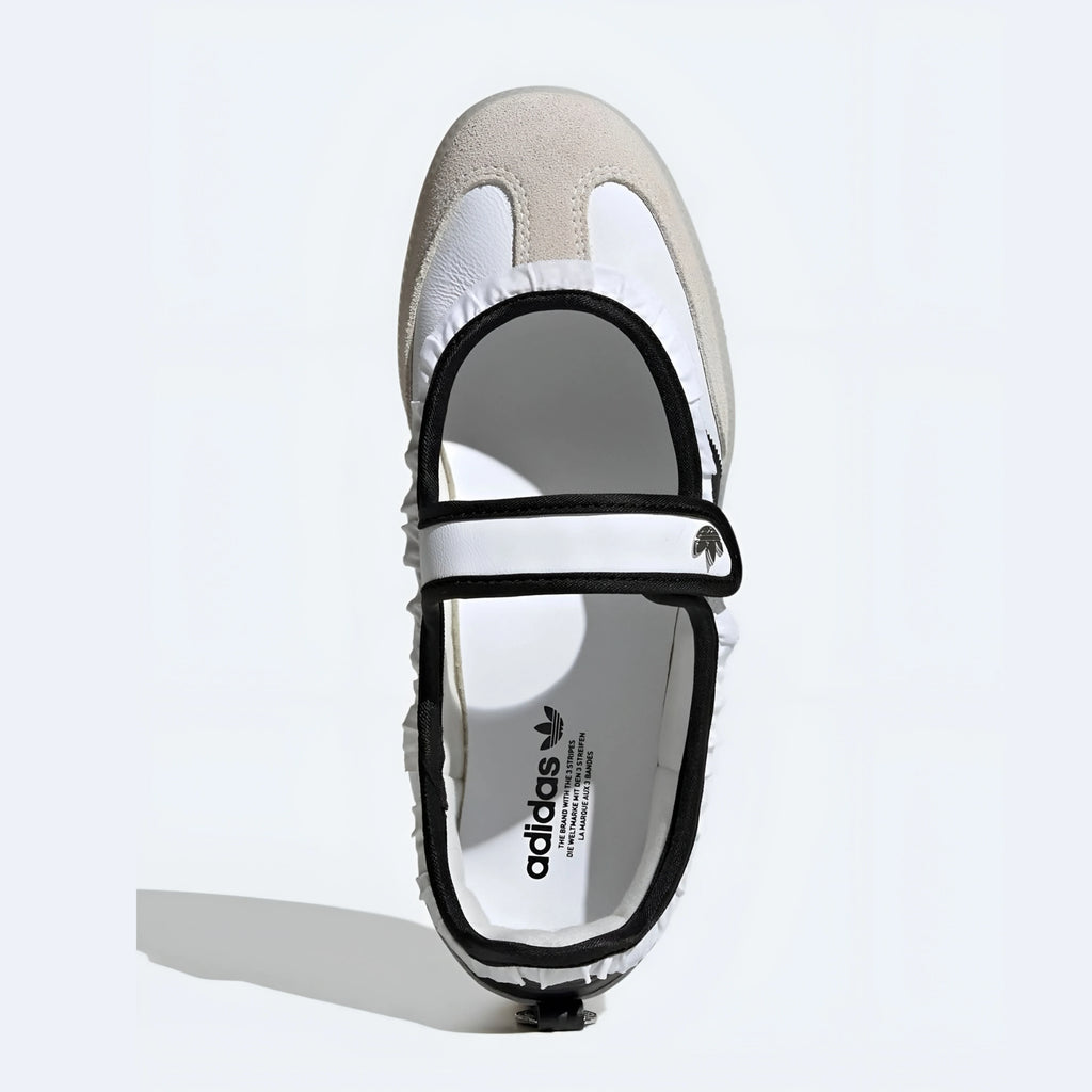 A single Adidas Mary Jane shoe in white and beige suede with black trim, shown from a top-down view on a light gray background.